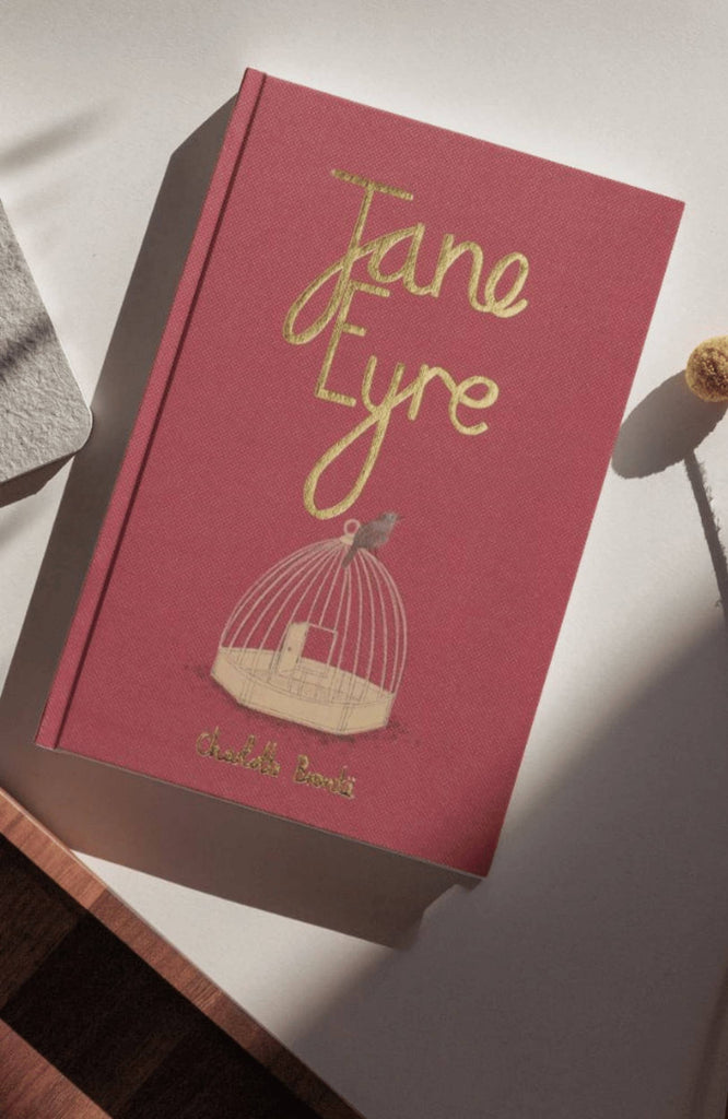 The "Jane Eyre | Brontë | Collector's Edition | Hardcover" with a red cover, gold lettering, and a birdcage illustration sits on a sunlit white surface.