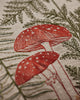The Coral & Tusk Mushrooms and Ferns Lumbar Pillow showcases linen fabric embroidered with red mushrooms, white spots, and green fern leaves for a botanical, nature-inspired accent.