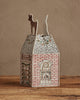 The Coral & Tusk Home for the Holidays Tissue Box Cover features a charming red brick house with embroidered windows, holiday lights, and a reindeer on a snowy roof—an ideal festive accent for your home.