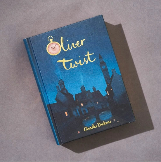 The Oliver Twist | Dickens | Collector's Edition | Hardcover Book features a dark blue cover with a Victorian-era town illustration and a pink pocket watch at the top left.