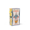 A rectangular box featuring Moulin Roty Pablo the Elephant from The Minouchkas, illustrated in yellow pants and a checkered hat by Lucille Michieli, with floral designs on a light background.