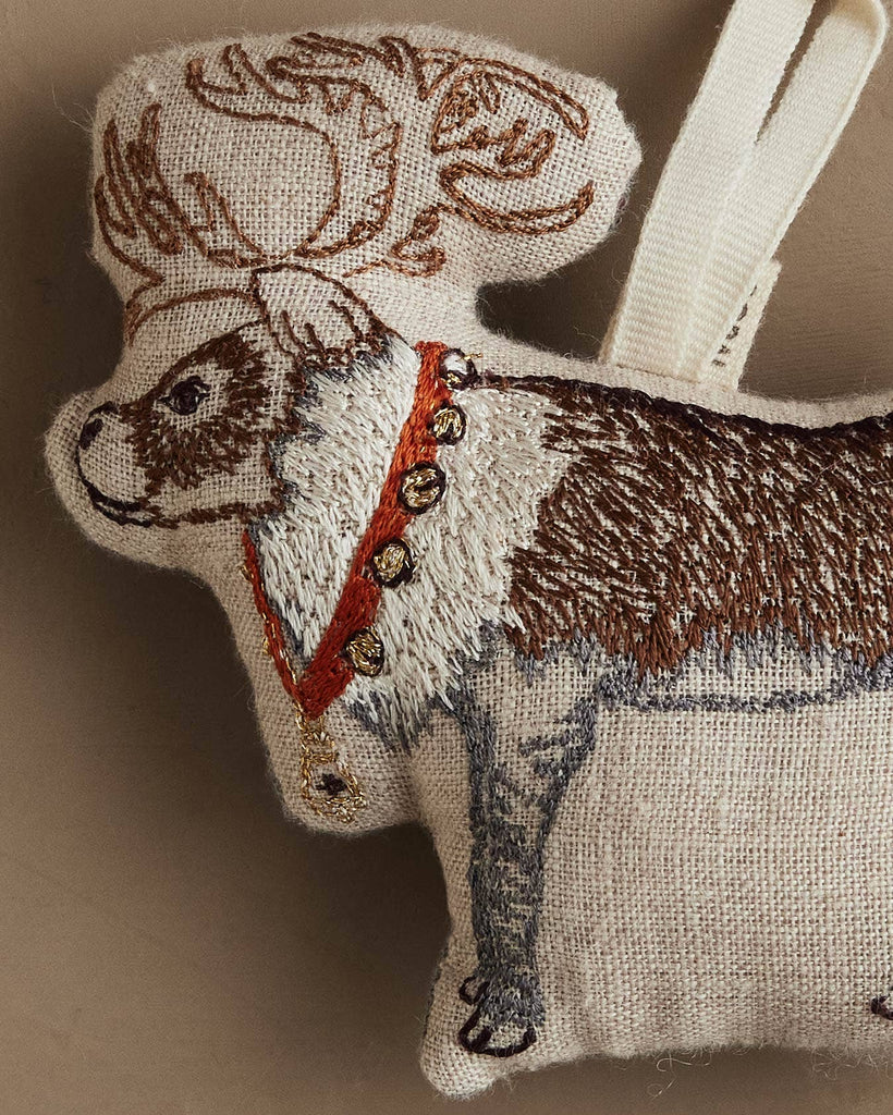 The Coral & Tusk Reindeer with Bells Ornament is a fabric holiday reindeer, embroidered in brown and white with a red collar, golden bells, and a cream hanging loop.