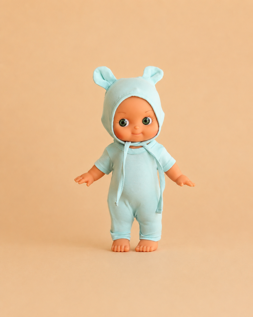A Minikane Mini Pancha Doll - Zebulon, dressed in a mint blue mouse outfit with charming ears, stands on a beige background facing forward with arms slightly outstretched. Crafted from high-quality vinyl, this delightful figure is perfect for inspiring imaginative play.