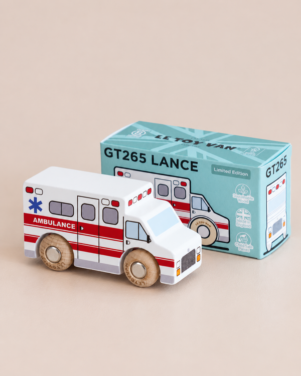 A charming wooden toy ambulance labeled “No. 43 GT265 Lance | Made in England” sits next to its coordinating box, both featuring matching colors and design details. Perfect for imaginative play, this delightful set inspires little ones to embark on their own rescue adventures.