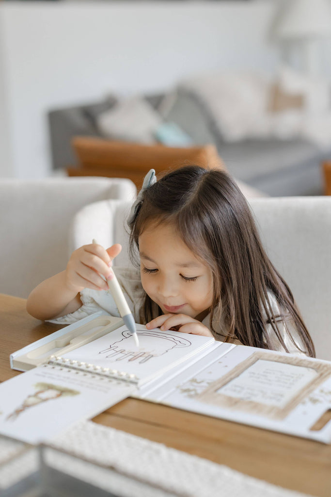 A young girl uses a water-filled pen to color a birthday cake illustration in a Winnie-the-Pooh: Pooh’s Birthday Surprise (Water Reveal) no-mess, reusable activity book.
