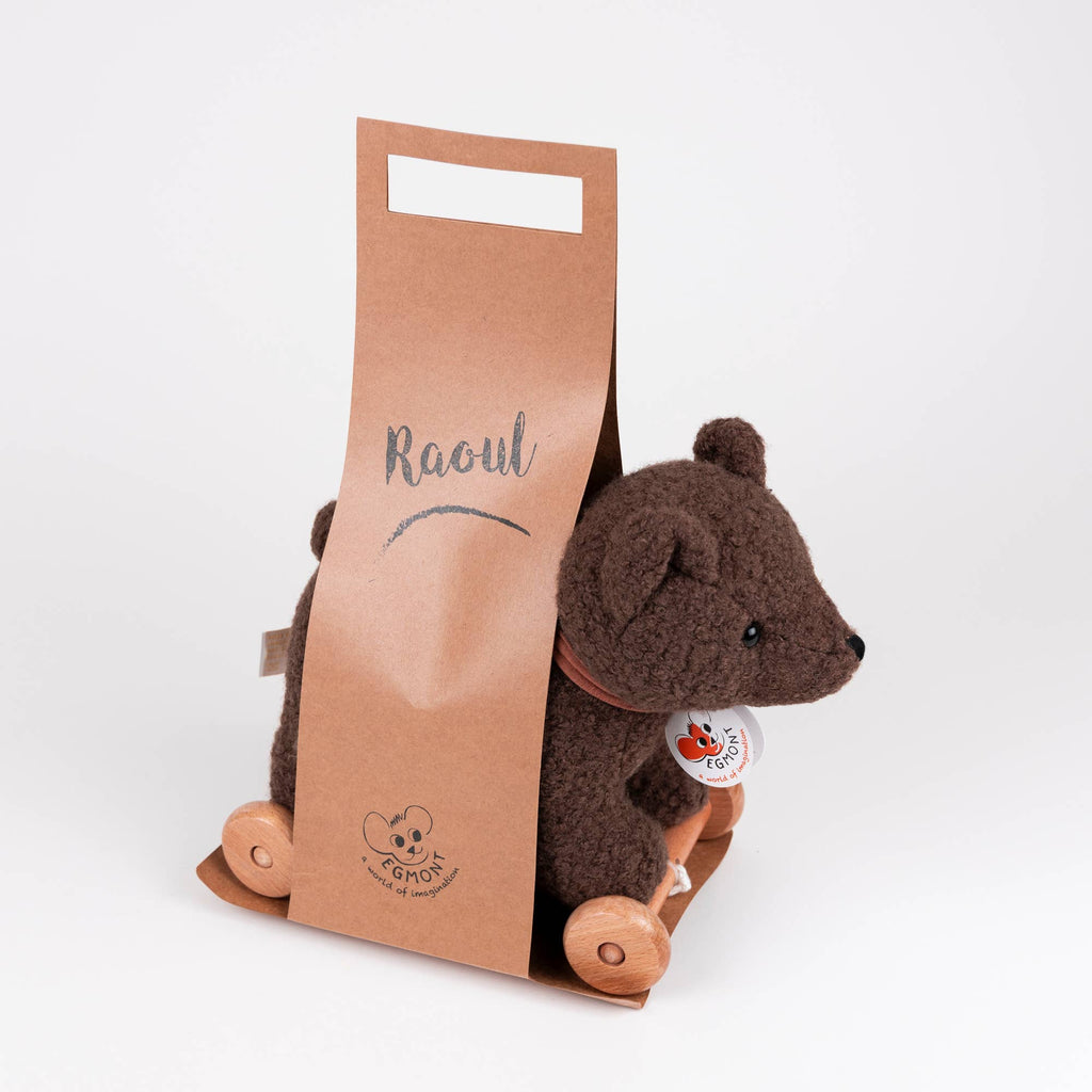 The Pull-Along Raoul features a plush brown bear on wooden wheels, complete with a round paper tag on its neck, showcased against a white background.