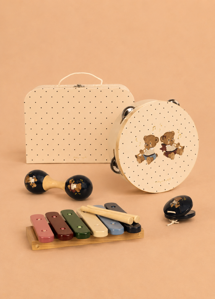 The Konges Sloejd Music Set - Teddy Bear is an adorable children’s instrument collection that includes wooden musical pieces like a tambourine, maracas, xylophone, and castanets, each adorned with cartoon bear designs and displayed in front of a lively polka-dot case on a soft beige backdrop.