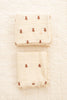 Two Organic Cotton Layered Gauze Baby Blankets - Teddy (ships in one week), cream-colored with small brown teddy bear patterns and lace-trimmed edges, are neatly folded side by side on a quilted white surface.