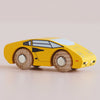 A No. 14 GT80 Lando, a small yellow wooden supercar with black detailing and wooden wheels, crafted in England and finished with a child-safe coating for safe and fun play, is placed on a light surface.