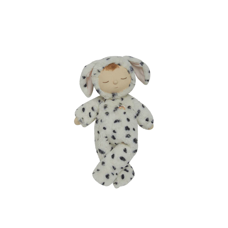 The Olli Ella Cozy Dinkum - Dog Domino is a soft plush doll with closed eyes, dressed in a white hooded onesie with black spots and floppy dog ears, shown against a plain white background.