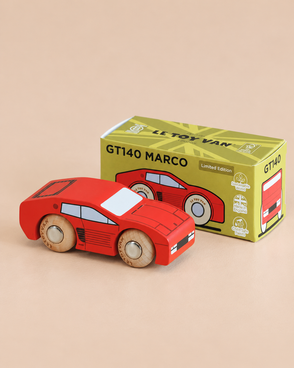 A red wooden No. 25 GT140 Marco racing car, made in England, sits next to its green and yellow box labeled “GT140 MARCO” and “Limited Edition,” which features motorsport-inspired illustrations of the classic toy car.