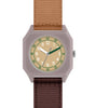 The Mini Kyomo Watch - Plum Cake features a square face, tan dial, white numbers, green second markers, brown and dark green hands, beige second hand, and brown/tan fabric straps.
