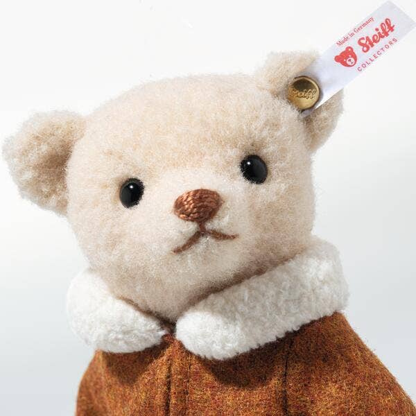 The Steiff Mama Teddy Bear With Child features cream-colored fur, black eyes, a brown nose, and a brown coat with a white collar. A "Steiff" tag on its ear marks it as a handcrafted holiday collectible for Christmas displays.