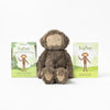A Slumberkins Bigfoot Kin + Lesson Book On Self Esteem stuffed with hypoallergenic fiberfill sits between two children's books titled "Bigfoot Copes with Hurt Feelings," featuring a happy, friendly design on a white background.