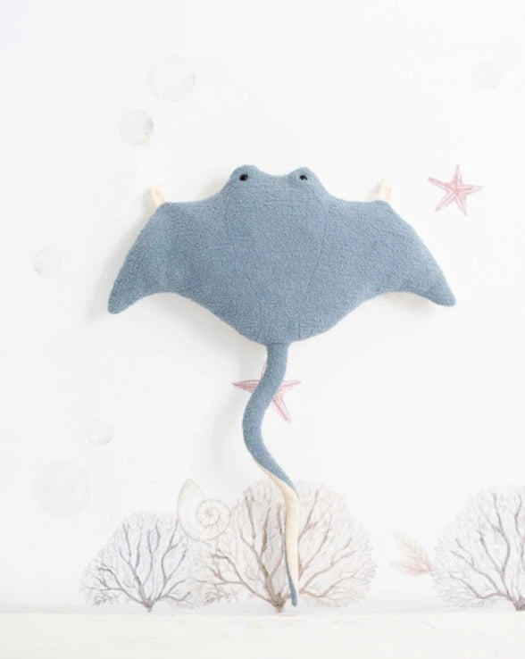 A soft, plush Light Blue Stingray mounted on a wall, surrounded by simple illustrations of underwater elements like bubbles and coral.
