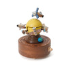 The Space Exploration Music Box features a yellow dome with satellites, rockets, and an airplane orbiting a small blue Earth, all set on a circular brown base with a hand crank.