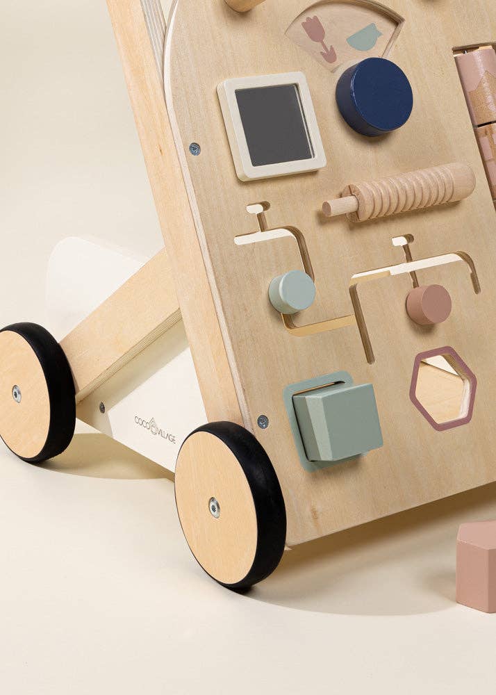 The Wooden Activity Walker features black wheels and a variety of interactive shapes, knobs, and cutouts designed as sensory toys for young children. The background is a light, neutral color.