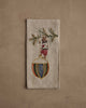The Coral & Tusk Deck the Halls Bear Tea Towel showcases an embroidered bear in festive attire standing on an ornament with a pine branch, adding cheerful holiday charm to your kitchen décor.