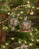 The Coral & Tusk Togetherness Deer Ornament hangs on a Christmas tree decorated with string lights, gold beads, and festive accents, beautifully capturing the spirit of togetherness.
