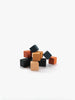 A small pile of Sabo Concept Mini Wooden Blocks - Tropics, featuring black, orange, and beige colors, is arranged on a white surface against a plain white background—perfect as educational toys for developing fine motor skills.