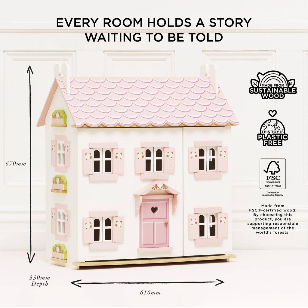 Sophie's Wooden Dolls House is a pastel pink, FSC-certified toy made from sustainable wood. Plastic-free, it features shutters and a door, and measures 670mm tall, 610mm wide, and 350mm deep. It stands against a light wall.