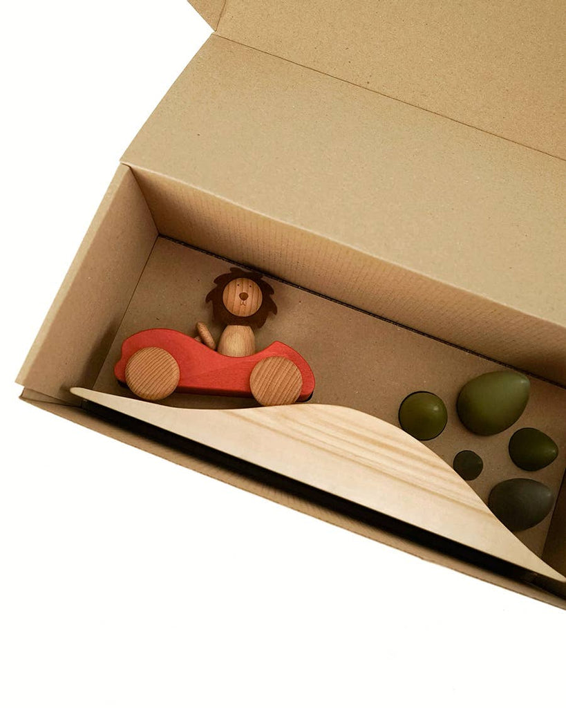 Sabo Concept First Journey comes in a cardboard box with a wooden toy lion in a red car, a light wood ramp, and green stone-shaped pieces—perfect for open-ended, imaginative play.