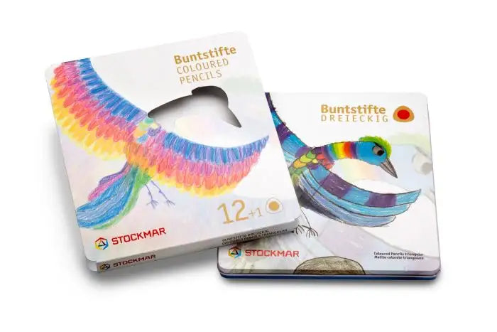 Two square tins of the Stockmar Triangular Colored Pencil Set (12 colors + graphite) are shown, each featuring a vibrant hand-drawn bird. One tin is closed; one open, revealing the bird through a pencil-tip cutout—classic German craftsmanship.