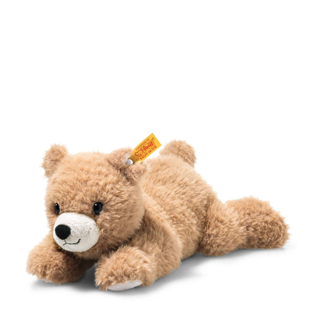 The Steiff Barny Brown Bear Stuffed Animal is a plush light brown bear with a white snout, black eyes, and a yellow tag in its left ear. Shown lying on its stomach against a plain white background—ideal for Teddy bear collectors.