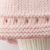 Close-up of Cuddle + Kind Clover the Bunny (Blossom) shows pale pink hand knit fabric with a decorative openwork row and ribbed cream section; handmade in Peru using fair trade practices.
