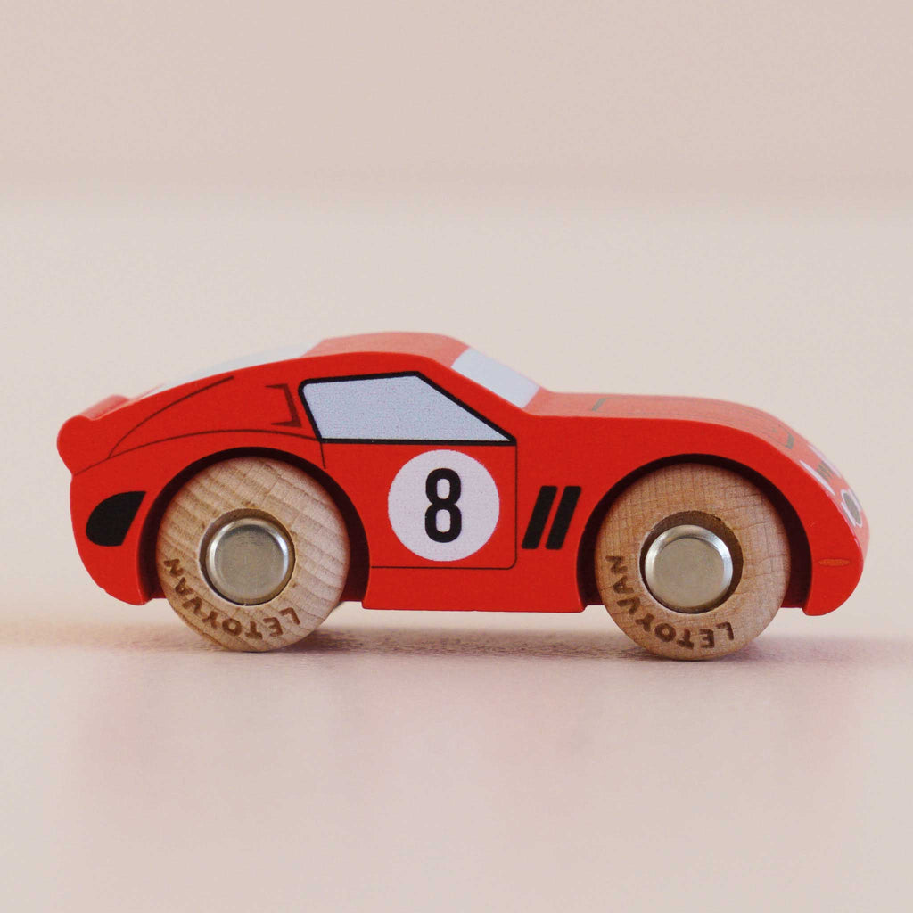 A compact, classic-style red wooden racing car—No. 4 GT25 Finley—crafted in England, featuring the number 8 on its side, sleek black accents, and natural wood wheels, displayed on a light surface.