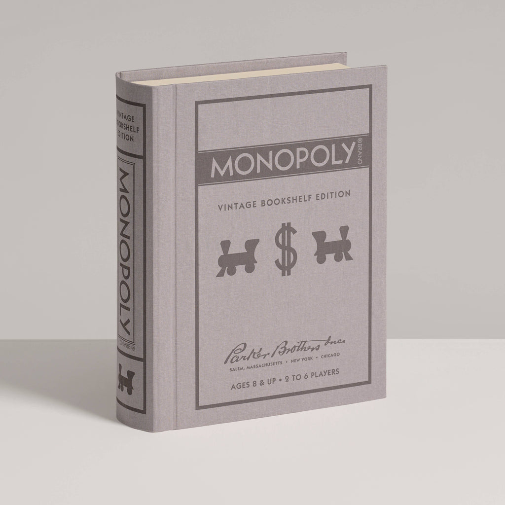 The Monopoly Vintage Bookshelf Edition is a gray hardcover book featuring premium game components, the game's title, classic game piece icons, and age/player info on the front cover.