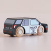 A No. 42 GT260 Liberty wooden toy police car—made in England, featuring a black body, white doors with “POLICE EMERGENCY” on the side, classic American styling, and wooden wheels—inspires imaginative storytelling as it’s displayed on a light surface.