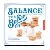 Box for the Balance the Baker Stacking Game showing a baker balancing wooden pastries. This fun stacking toy, suitable for one or more players, features the Kikkerland brand name on the right side.