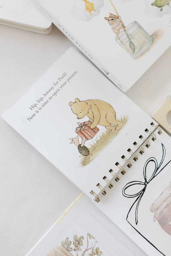 Winnie-the-Pooh: Pooh’s Birthday Surprise (Water Reveal) spiral-bound book showing an illustration of Pooh and Piglet holding a gift, with the text, “Hip, hip, hooray for Pooh! Now it is time to open your present.”