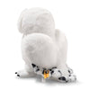 A Steiff Harry Potter "Hedwig" Owl 8" plush toy, white with black-tipped wings and tail, sits upright facing away with a yellow tag attached to its wing.