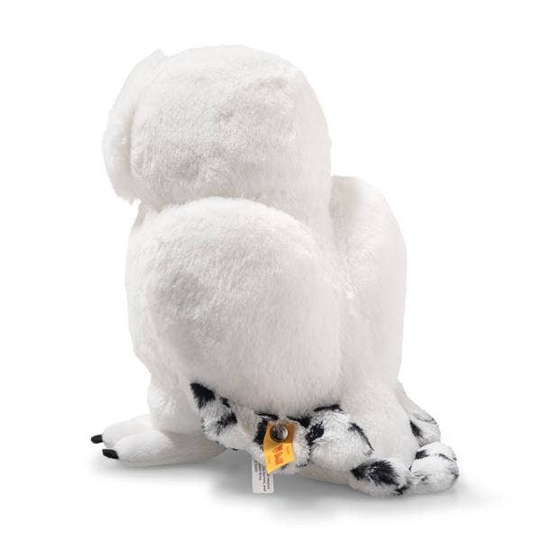 A Steiff Harry Potter "Hedwig" Owl 8" plush toy, white with black-tipped wings and tail, sits upright facing away with a yellow tag attached to its wing.