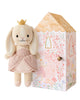 Cuddle + Kind Tiny Rose the Princess is a fair trade, hand-knit bunny doll in a pink dress with a golden crown, standing beside a decorative box featuring floral patterns and a princess illustration.