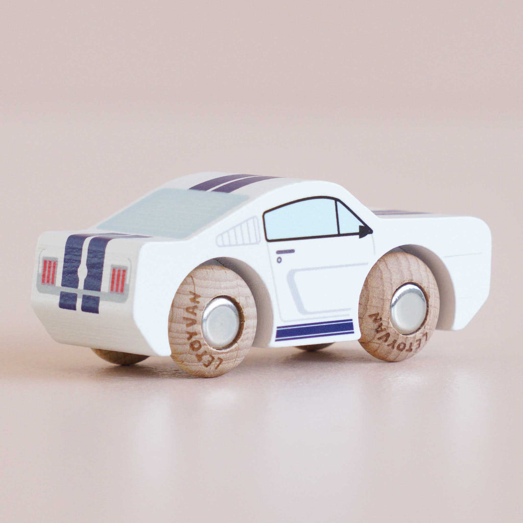 A small white No. 17 GT95 Maverick muscle car toy with blue racing stripes and wooden wheels, made in England, photographed on a light beige surface.