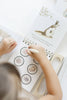 A child uses a water pen to reveal illustrations of food on a page of a Winnie-the-Pooh: Pooh’s Birthday Surprise (Water Reveal) book featuring Kanga and Roo.