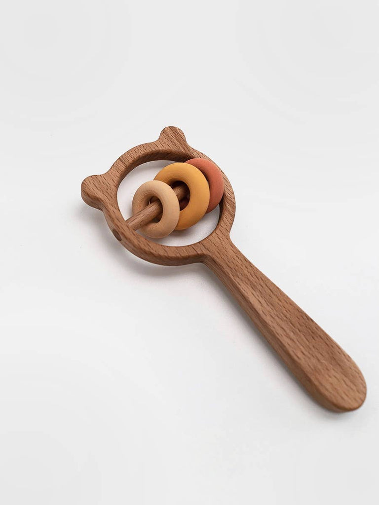 The Sabo Concept Bear and Rings Rattle - Yellow and Pink is a wooden rattle with a bear-shaped frame, handle, and three colorful rings. This charming toy supports motor skills development and is shown on a plain white background.