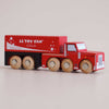 A red and black wooden truck labeled “No. 33 GT180 Toby | Made in England” with six wooden wheels on a light background. Featuring vintage-inspired design elements, the truck has white details and playful bubble graphics on the side, making it perfect for imaginative storytelling.