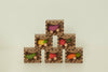 Six small cardboard boxes hold Sweetie The Strawberry Baby Car, an eco-friendly toy vegetable on wheels, stacked in a pyramid against a plain light background. This charming baby car toy is shaped like a strawberry.