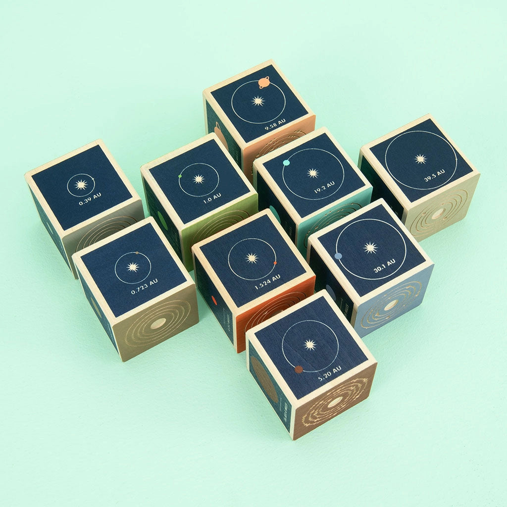 A collection of Uncle Goose Planet Blocks with celestial patterns and solar system planets printed in gold on a teal background.