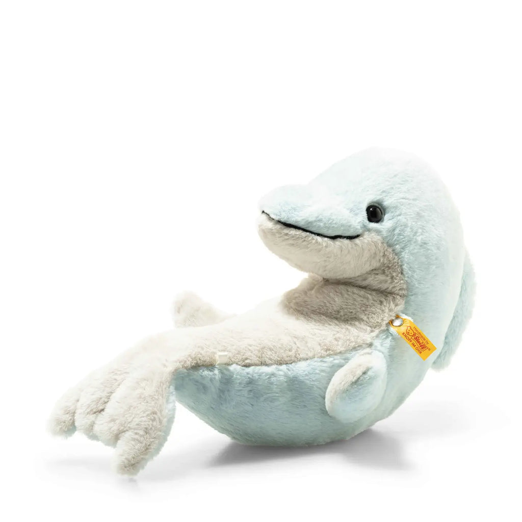 A Steiff Dolphin Stuffed Plush Animal named Denny Dolphin in a sitting position with a light blue and white body, featuring a smiling expression. The toy has the distinctive Steiff Button in Ear and a visible tag on.