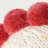 Close-up of a cream-colored knitted fabric with multicolored specks and red pom-poms along the edge, crafted in the tradition of heirloom-quality Cuddle + Kind Baby Chicken dolls handmade in Peru.