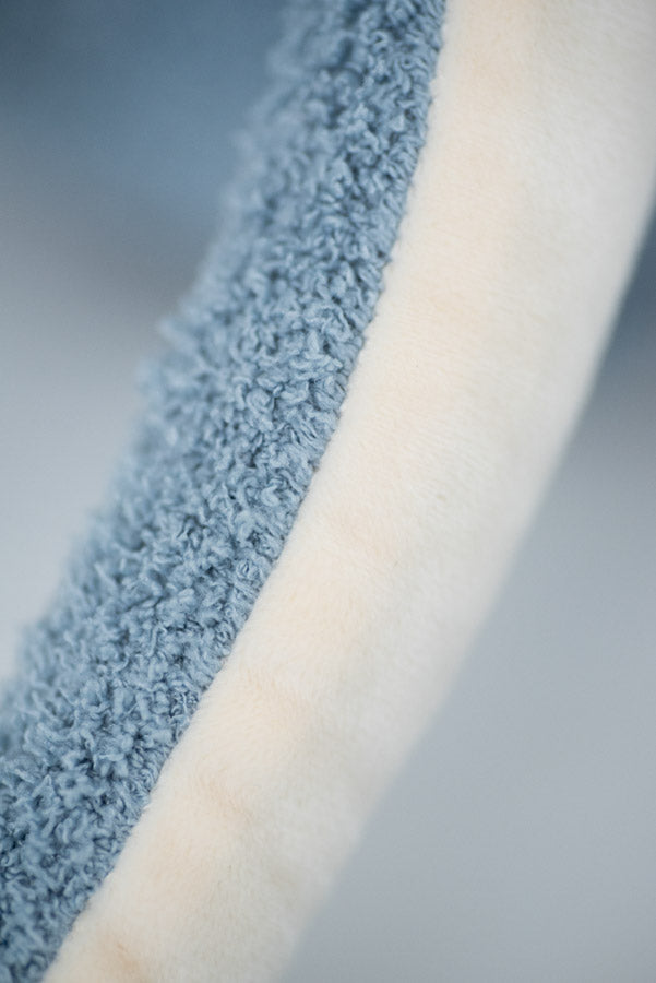 Close-up view of dual-textured fabric, featuring a strip of soft plush white material alongside a textured blue-grey fabric, perfect for Octopus Stuffed Animal room decoration.