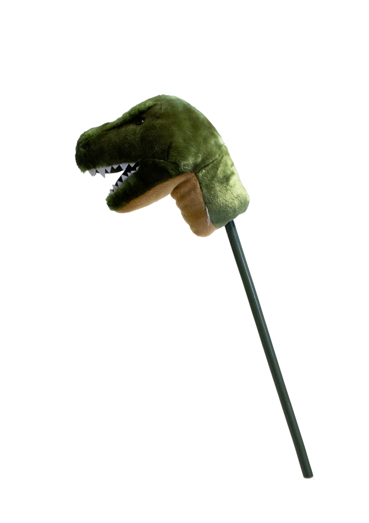 The Hobbyhorse - T-Rex Dino features a plush green dinosaur head with white fabric teeth and a brown underside, mounted on a stick—perfect for imaginative play.