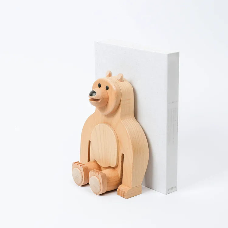 A Wooden Big Bear Bookend with a simple, stylized design sitting next to a white block on a light background. The bear has a cheerful expression and is made of responsibly-sourced, light-colored solid wood.