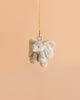 The Bukowski - August Elephant XL Bag Charm, a plush elephant keychain, hangs from a beige ribbon against a plain light peach background, making it an adorable accessory for any bag charm enthusiast.