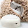 A cream-colored, round power bank with a USB port sits beside an open fuzzy pouch lined with soft teddy bear fabric from the Light at Night Caspar Teddy Bear Stuffed Plush, 11 Inches collection, partially revealing its cozy interior.